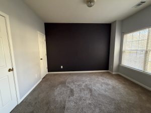 Bright flex room with large window, neutral carpet, and accent wall—ideal as a home office or fourth bedroom in 3-bedroom, Decatur townhome for rent in a gated community.